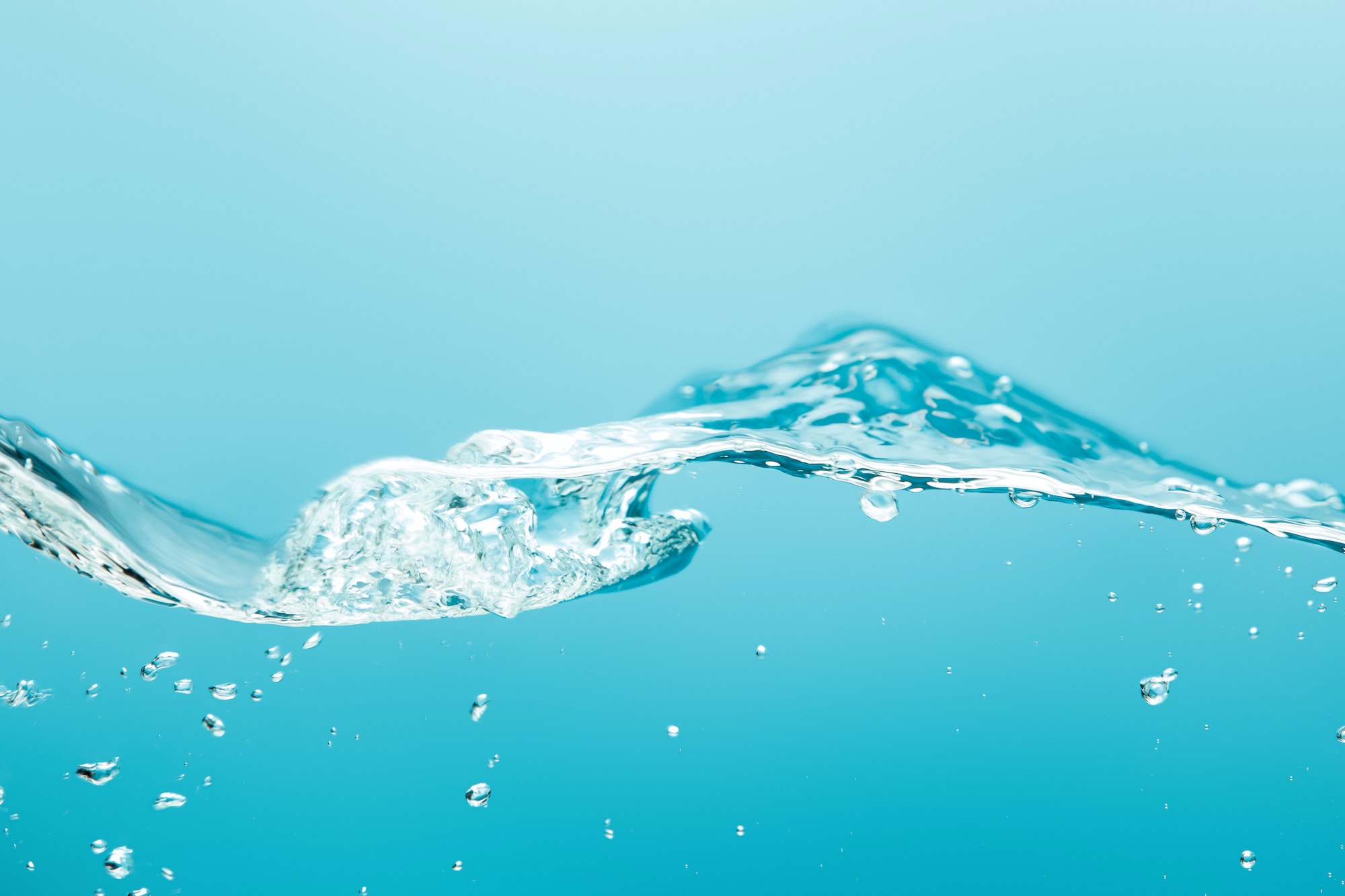 transparent pure water with splash and bubbles on blue background